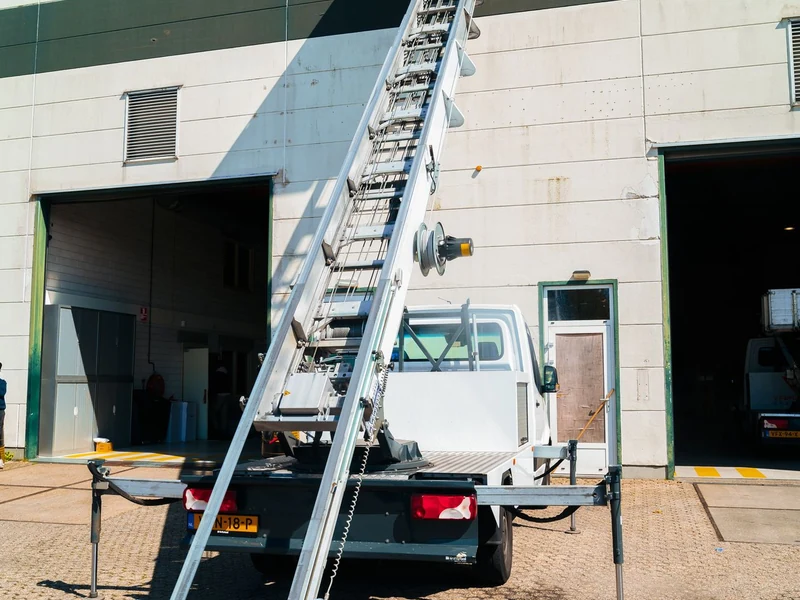Witte verhuislift met uitgeschoven ladder bij een loods