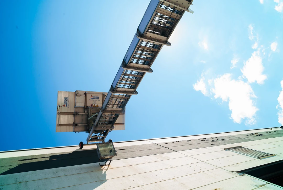 Uitgeschoven ladderlift tegen een blauwe lucht