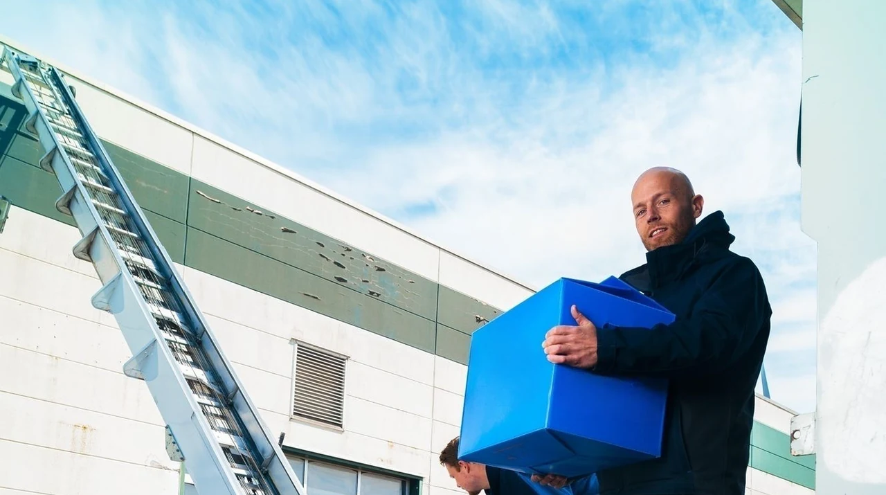 Operators met verhuisdozen bij een witte lift