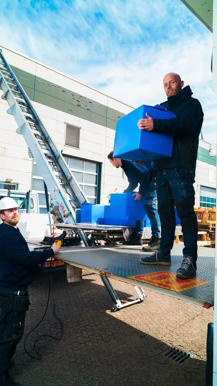 Operators laden dozen op het plateau van een witte verhuislift
